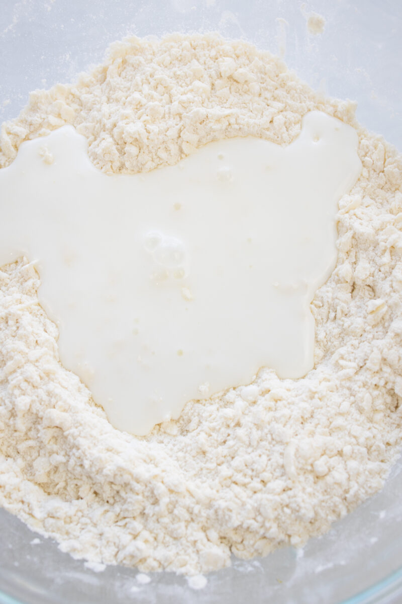 Overhead view of buttermilk being added to the biscuit dough.