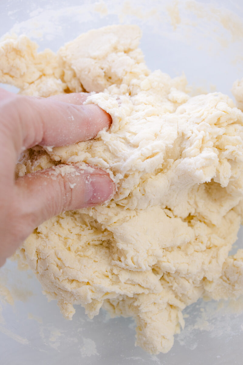 Overhead view of biscuit dough being placed on a surface.