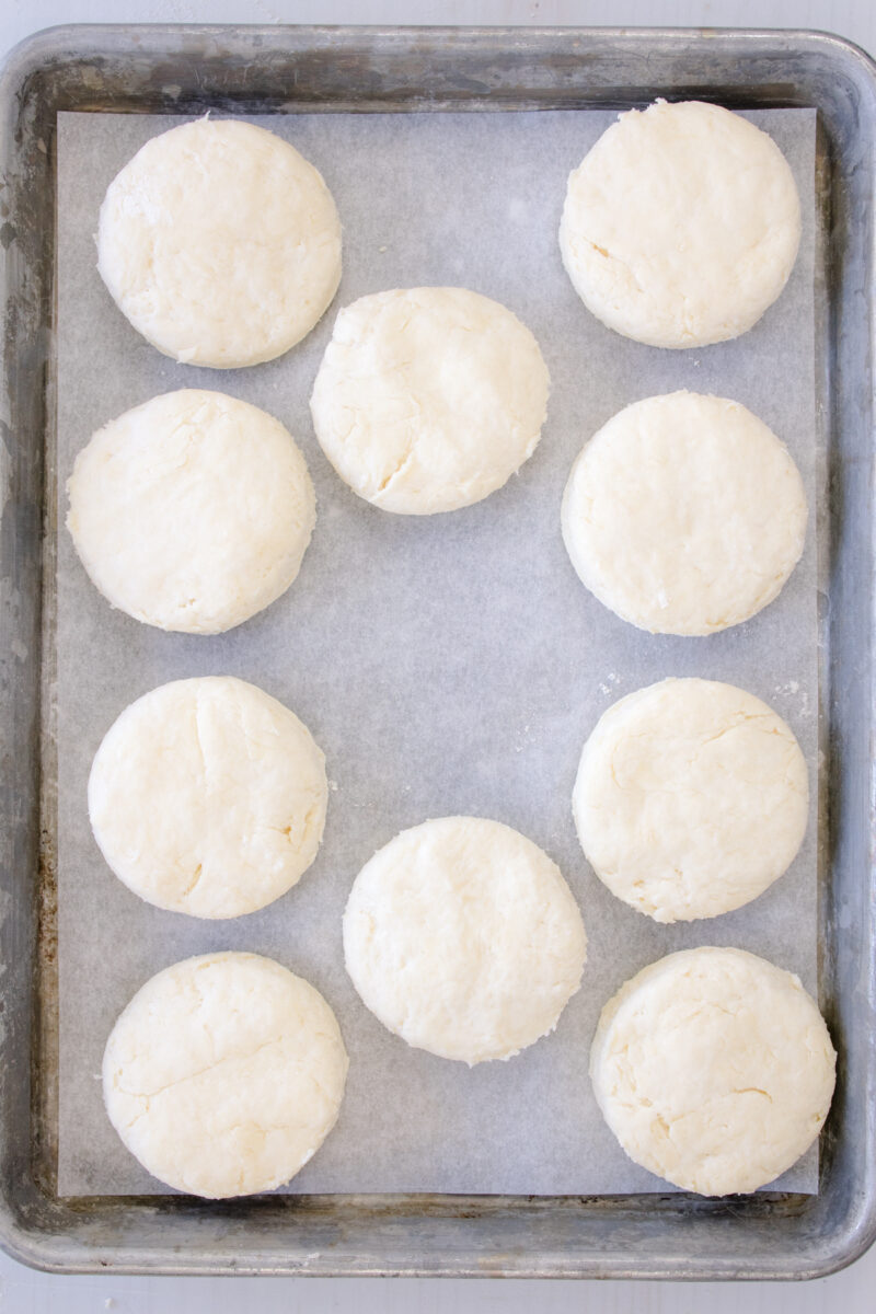 Overhead view of unbaked biscuits on a baking tray lined with parchment paper.