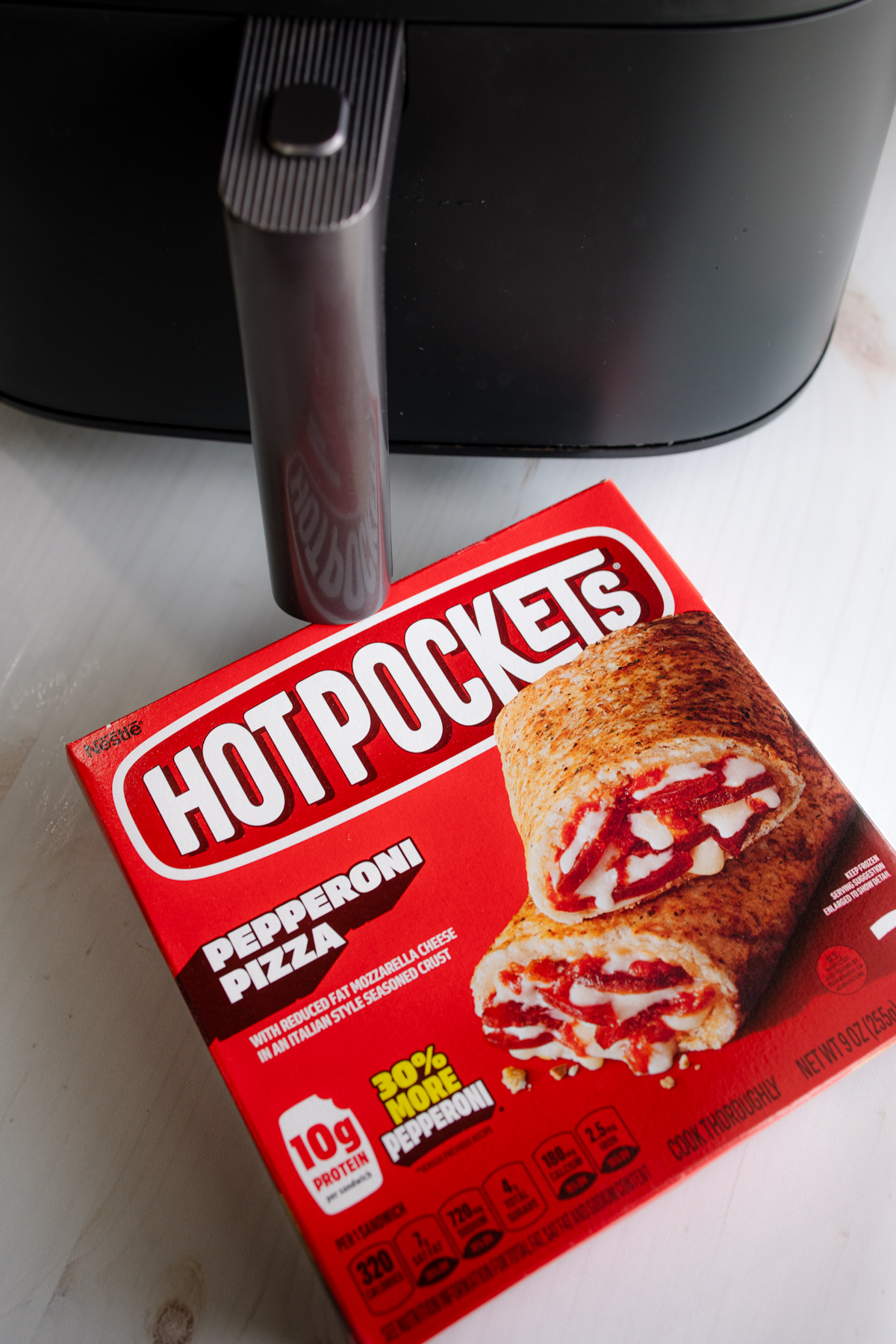 Angled view of a box of hot pockets in front of an air fryer.
