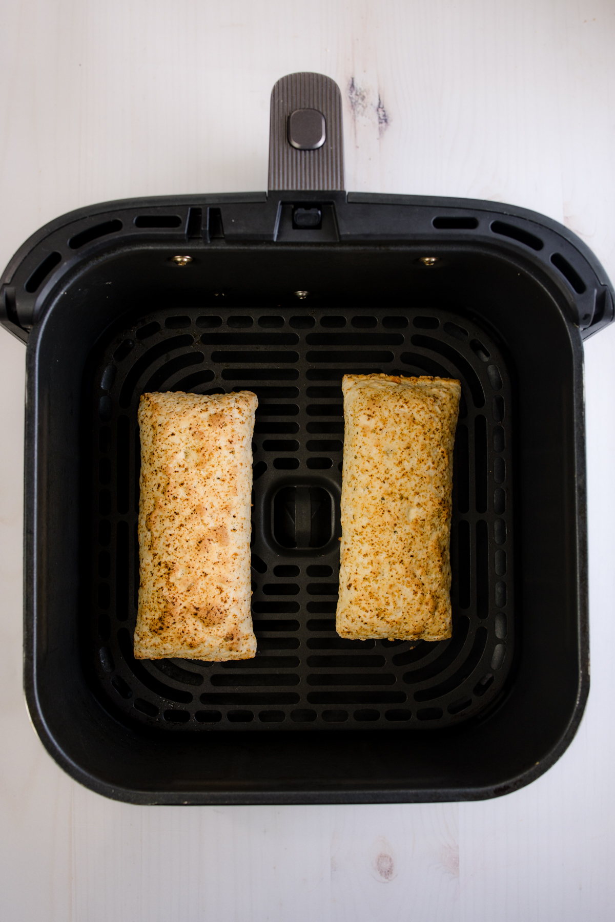 Overhead view of two hot pockets in an air fryer basket.