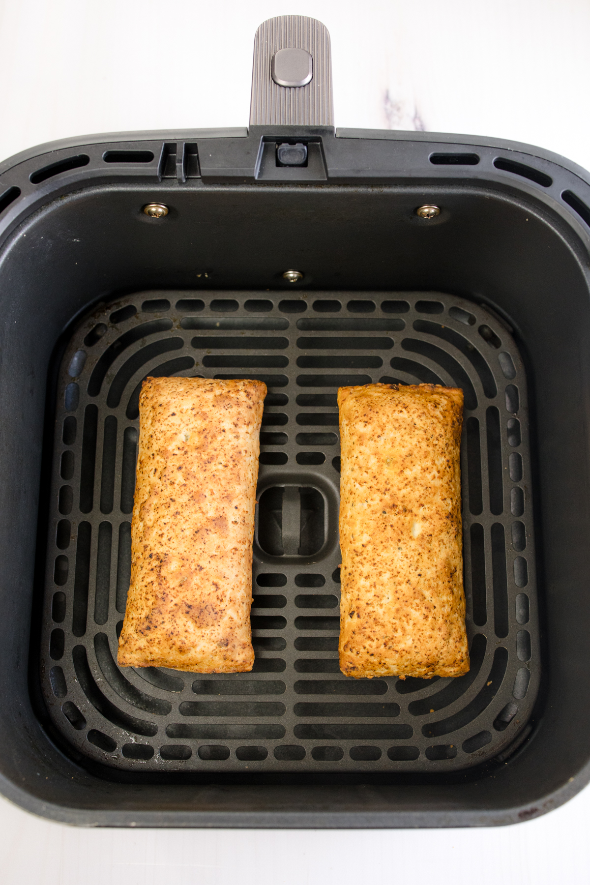 Overhead view of two hot pockets in an air fryer basket.