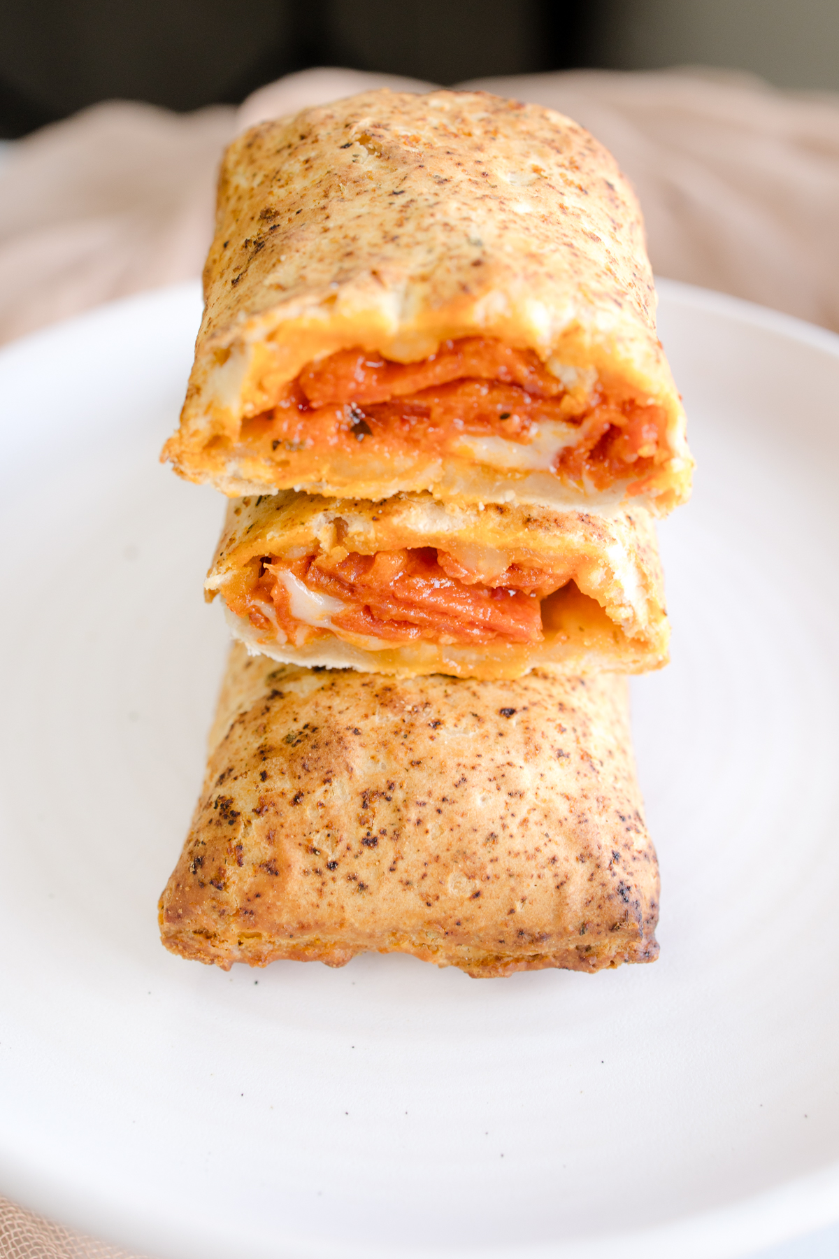 Close up view of a Hot Pocket sliced in half to reveal the middle, on a white plate.