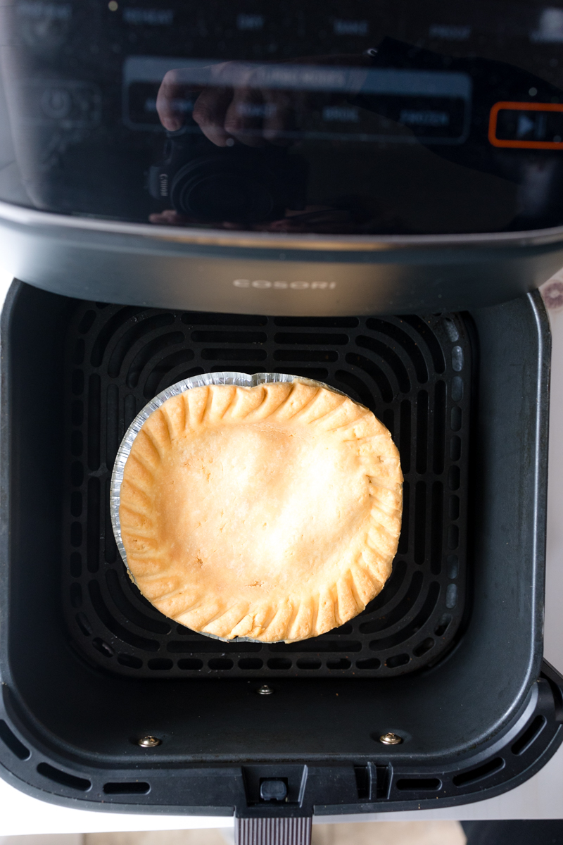 Angled view of a cooked pot pie in an air fryer basket.
