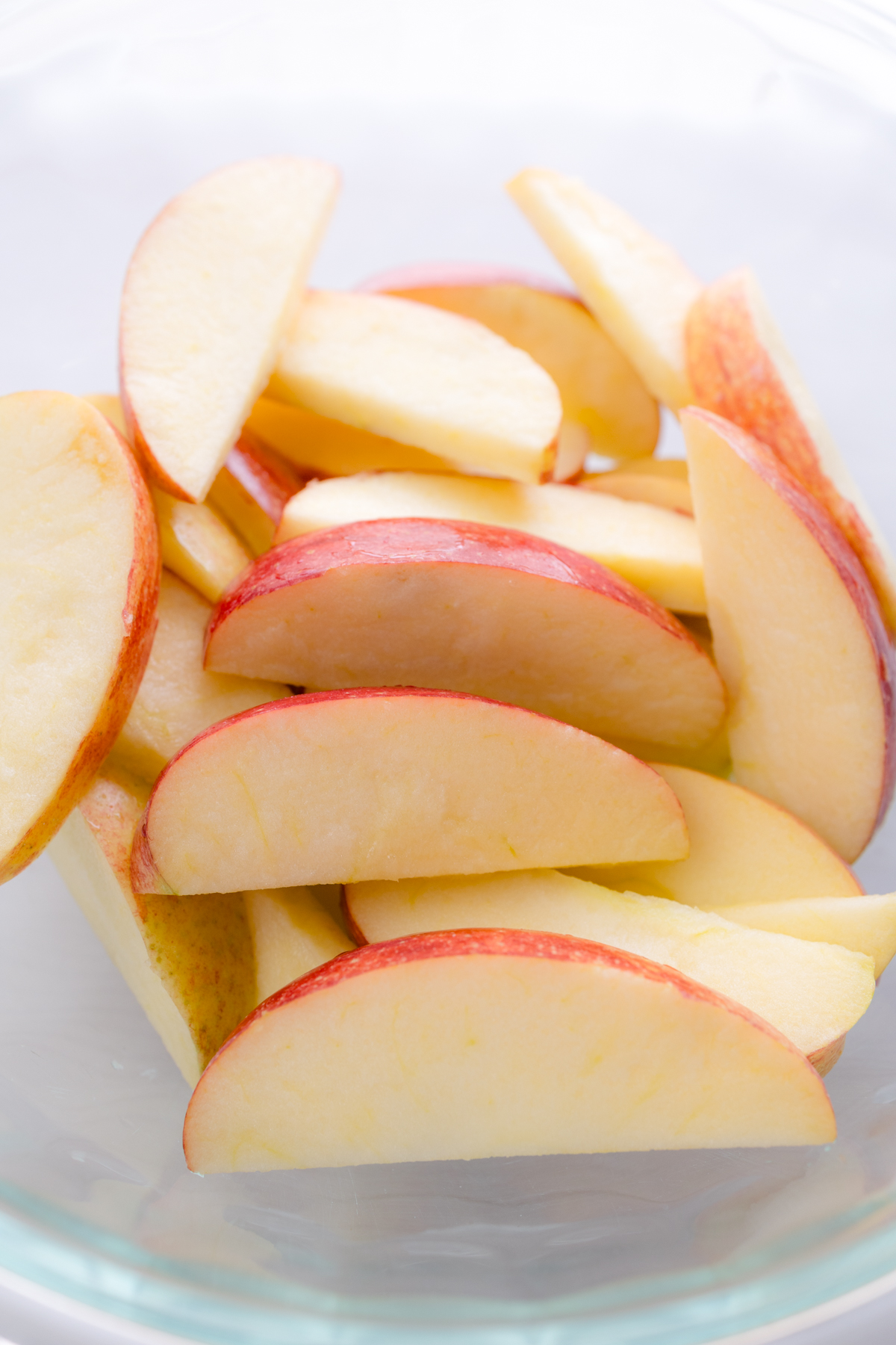 Overhead close up view of raw apples in a glass dish.