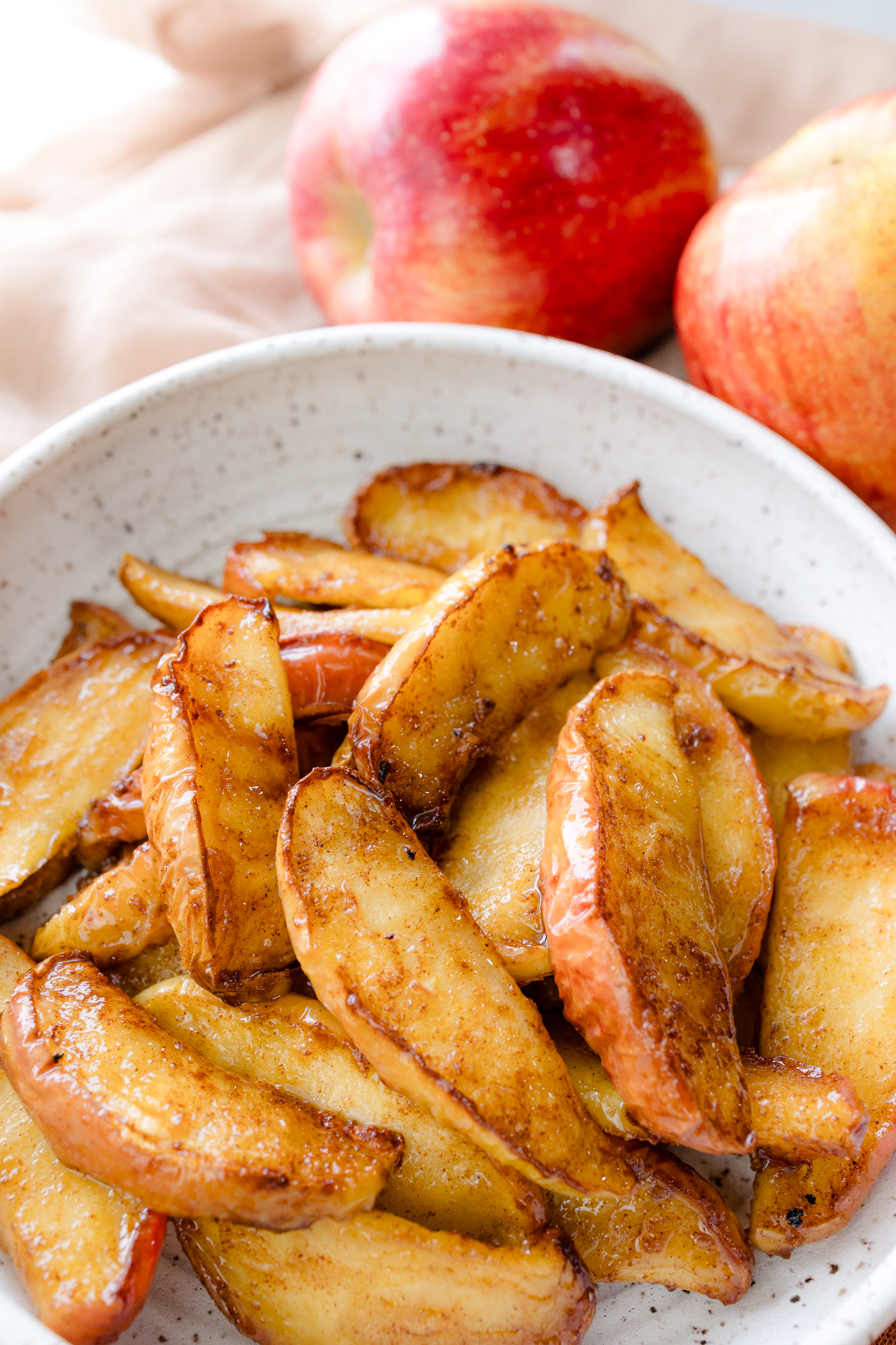 Overhead view of Air Fryer Apples in a bowl next to a couple of apples.
