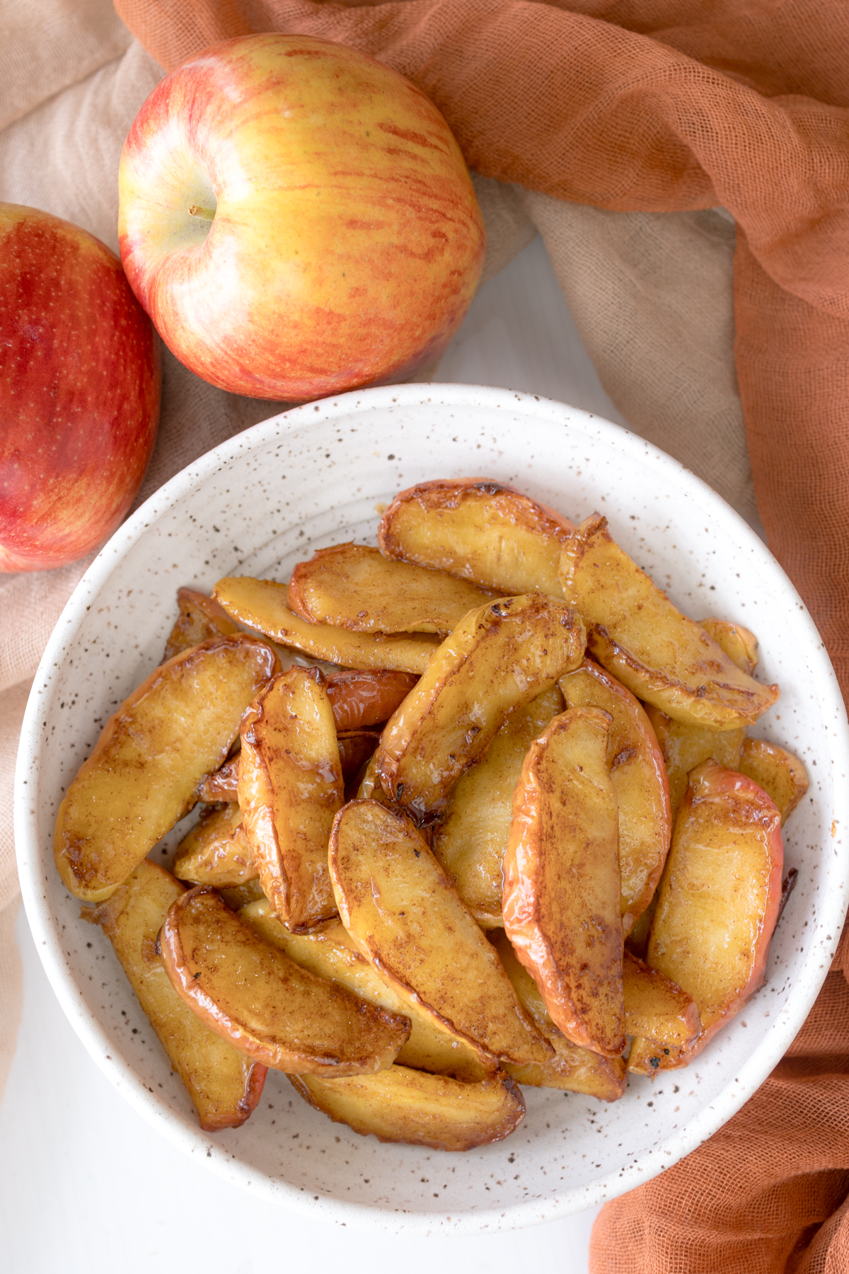 Overhead view of Air Fryer Apples in a bowl next to a couple of apples.