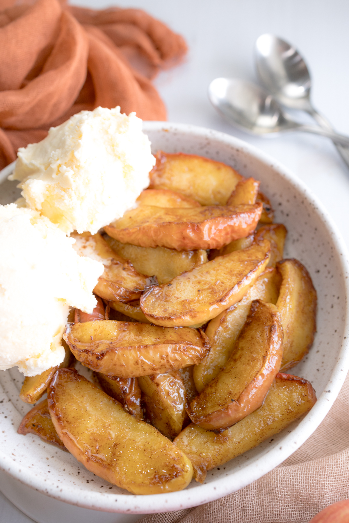 Angled close up view of Air Fryer Apples in a bowl with vanilla ice cream.