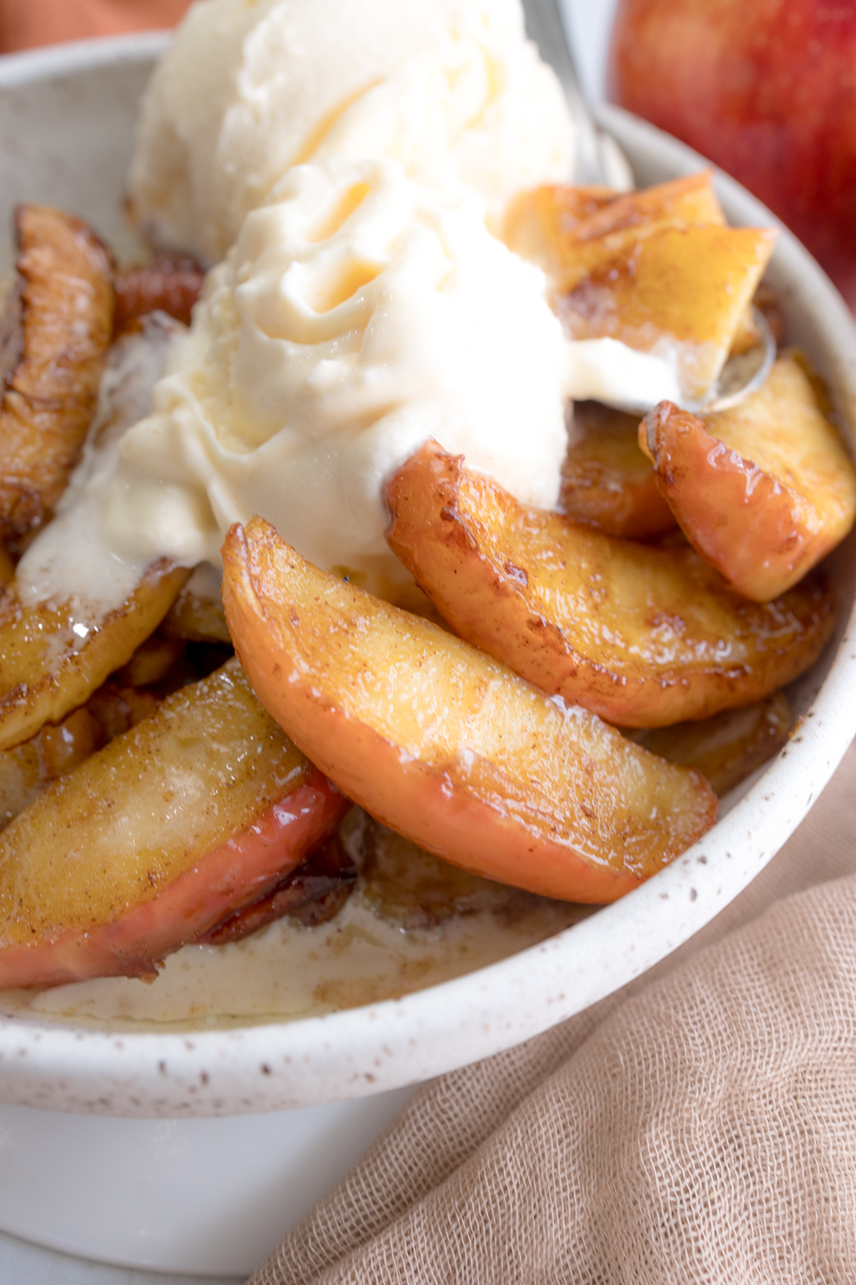 Angled close up view of Air Fryer Apples in a bowl with vanilla ice cream.