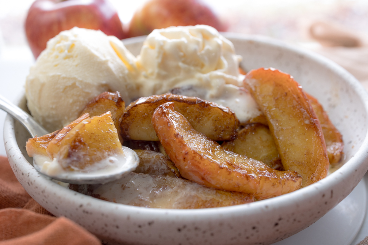 Angled close up view of Air Fryer Apples in a bowl with vanilla ice cream.
