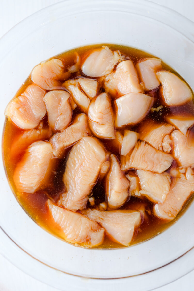 Overhead view of uncooked chicken Teriyaki marinating in a glass bowl