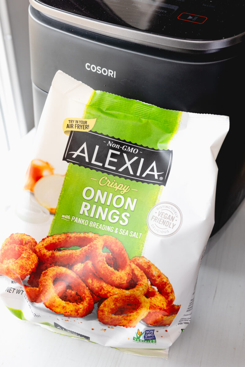 Angled view of a bag of Onion Rings in front of an air fryer.