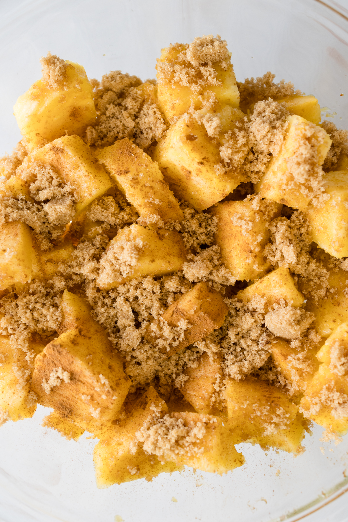 Close up overhead view of pineapple chunks in a glass dish, combined with other ingredients.