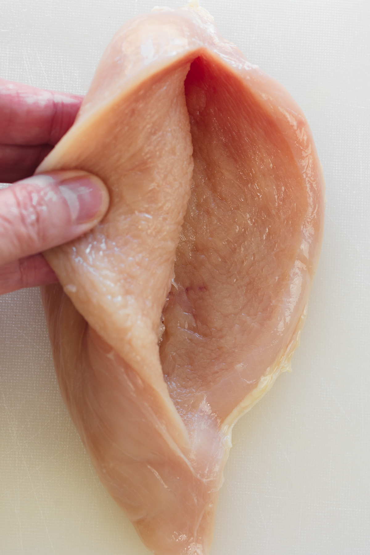 Close up overhead view of a sliced chicken breast being opened up.