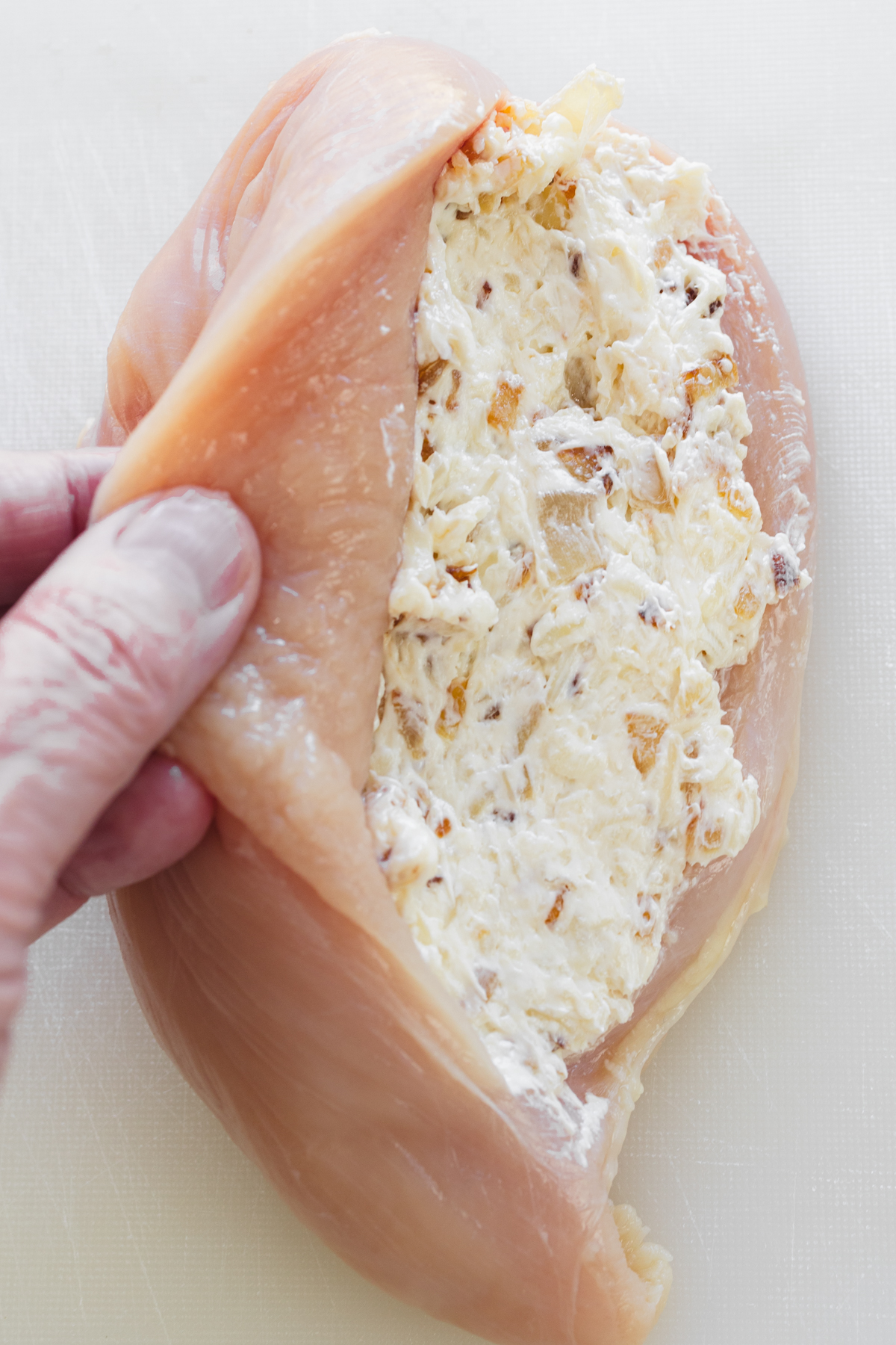Close up overhead view of a sliced chicken breast that's been stuffed with filling, still open.