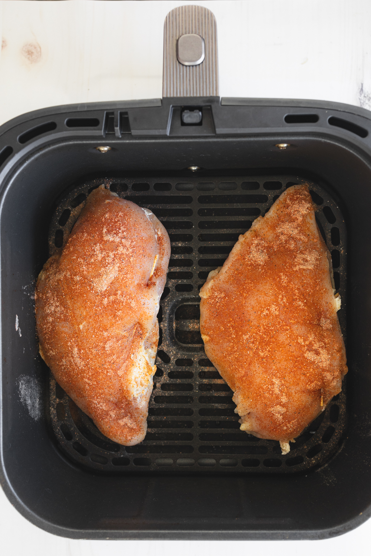 Overhead view of uncooked Air Fryer Stuffed Chicken in an air fryer basket.