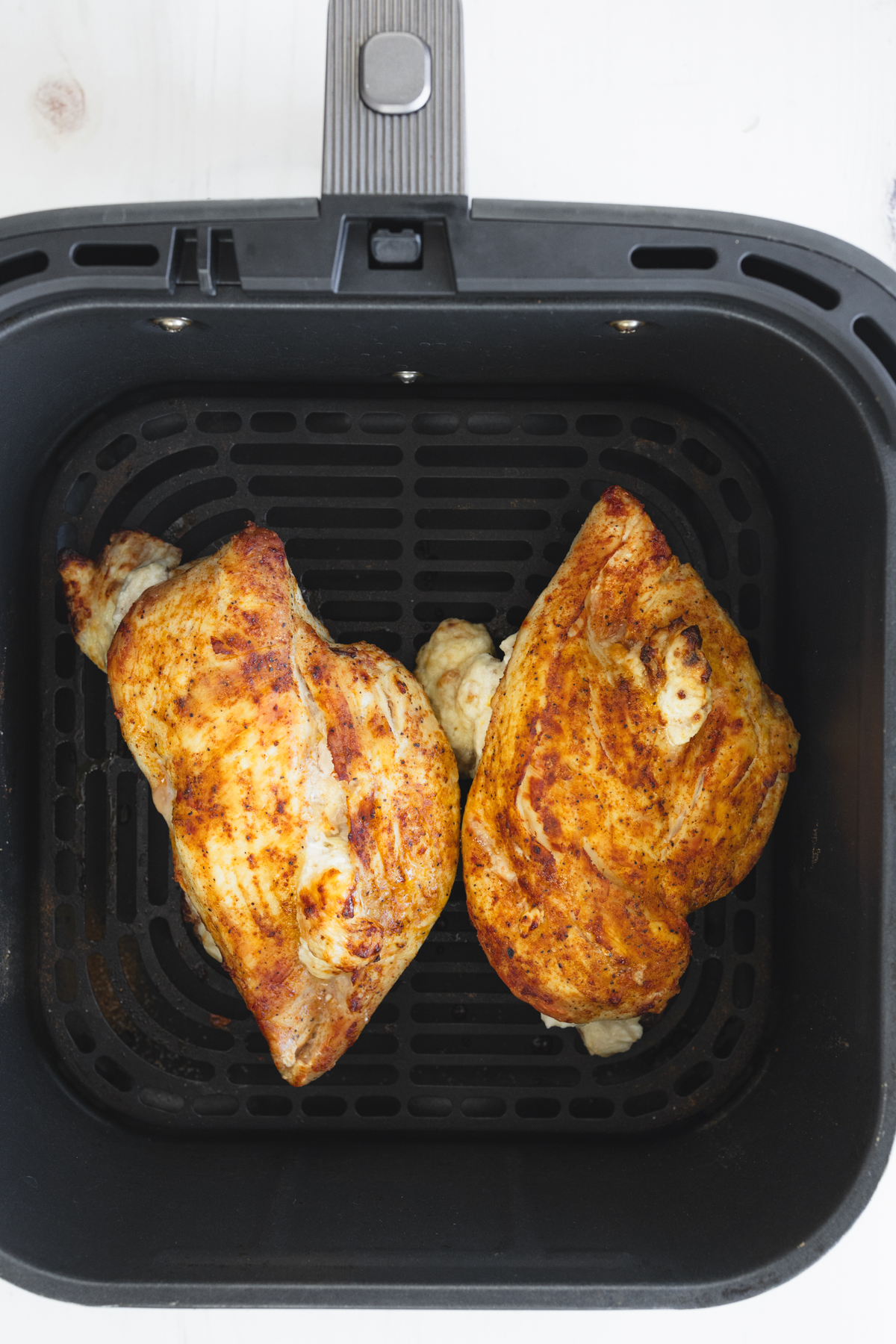 Overhead view of cooked Air Fryer Stuffed Chicken in an air fryer basket.