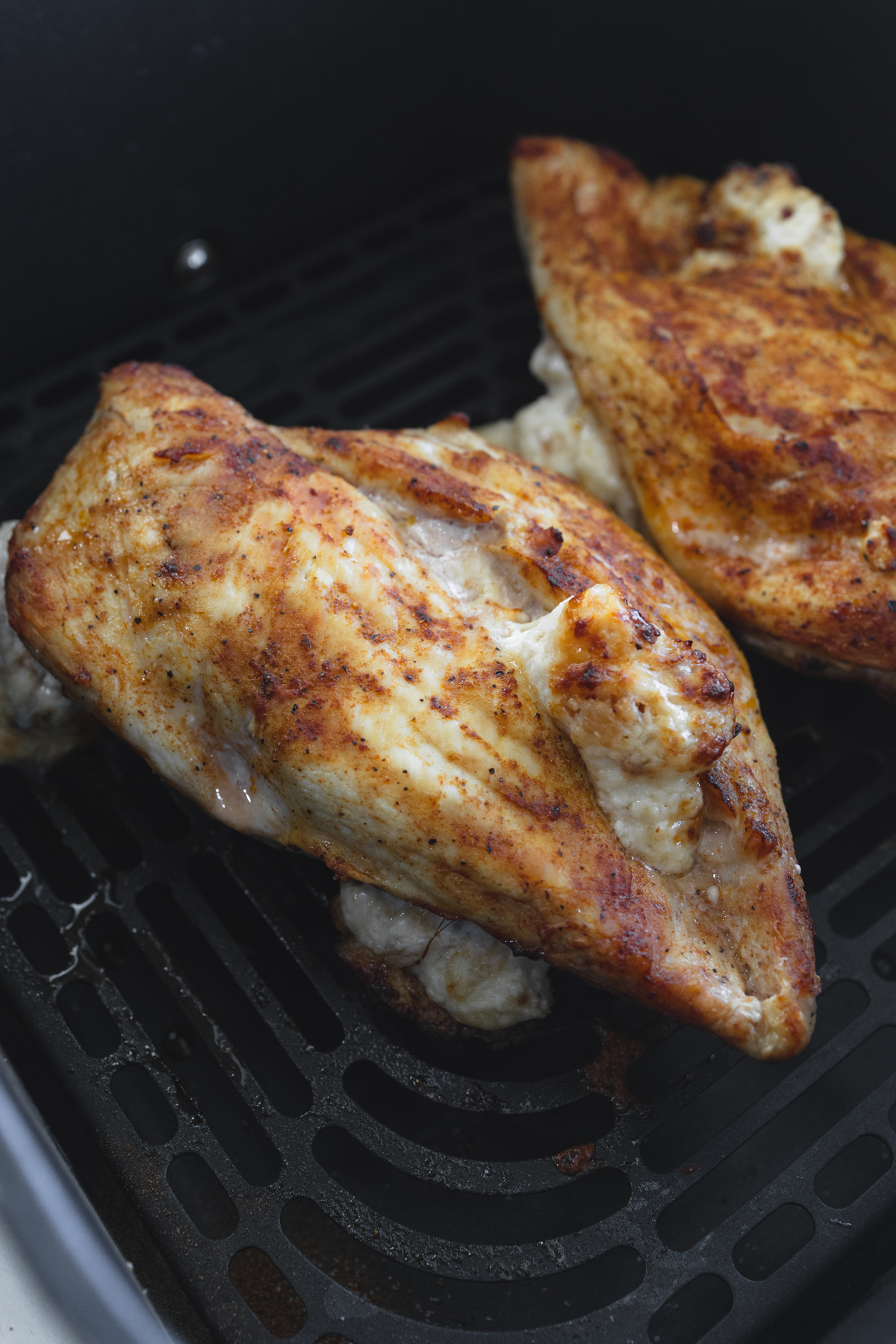 Close up view of cooked Air Fryer Stuffed Chicken in an air fryer basket.