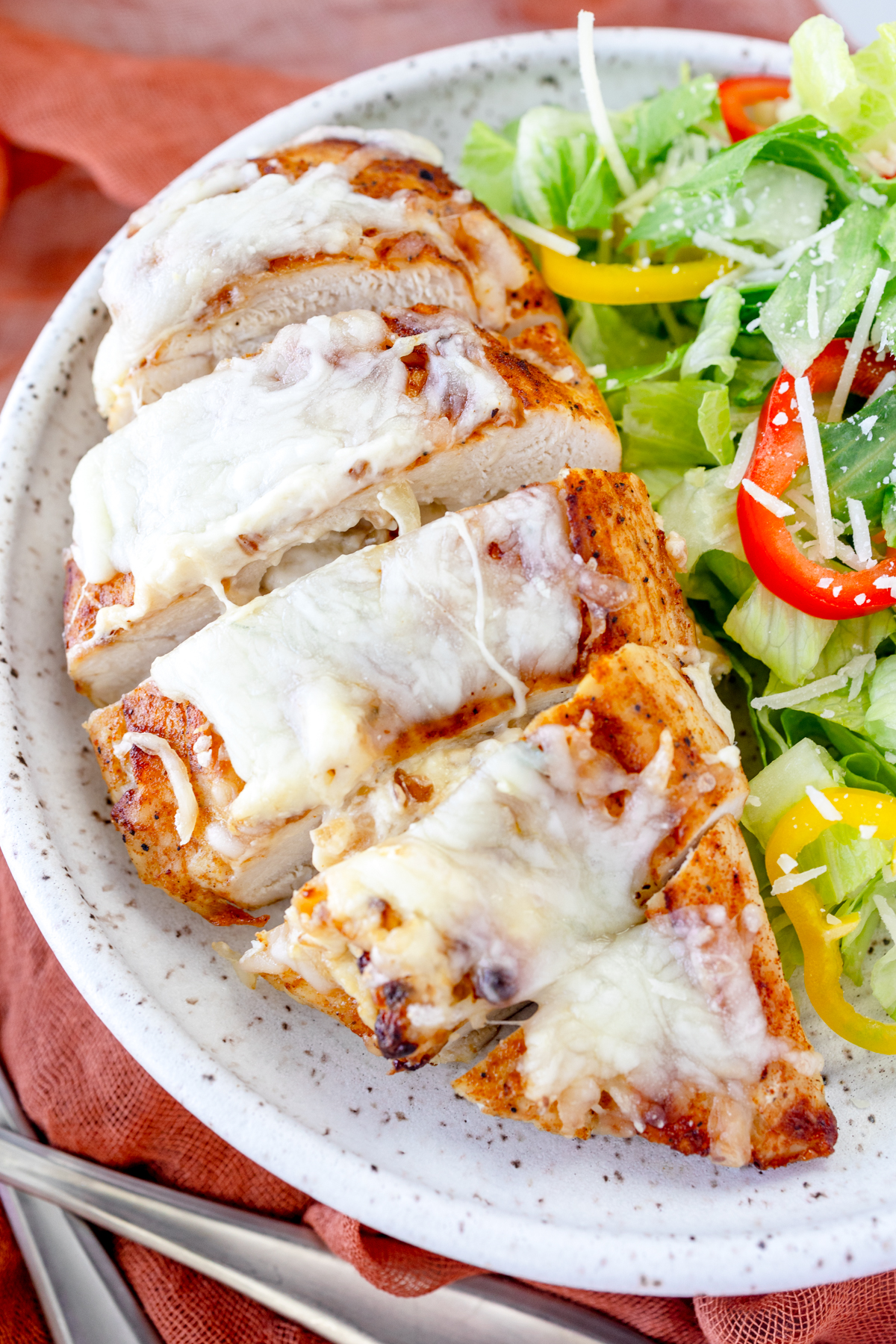 Angled close up view of Air Fryer Stuffed Chicken on a plate with salad.