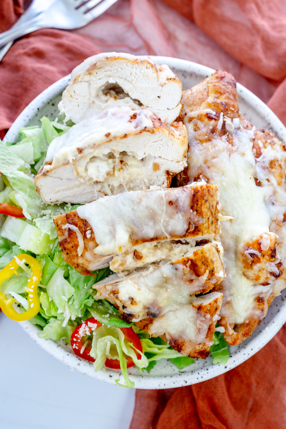 Overhead view of Air Fryer Stuffed Chicken on a plate with salad.