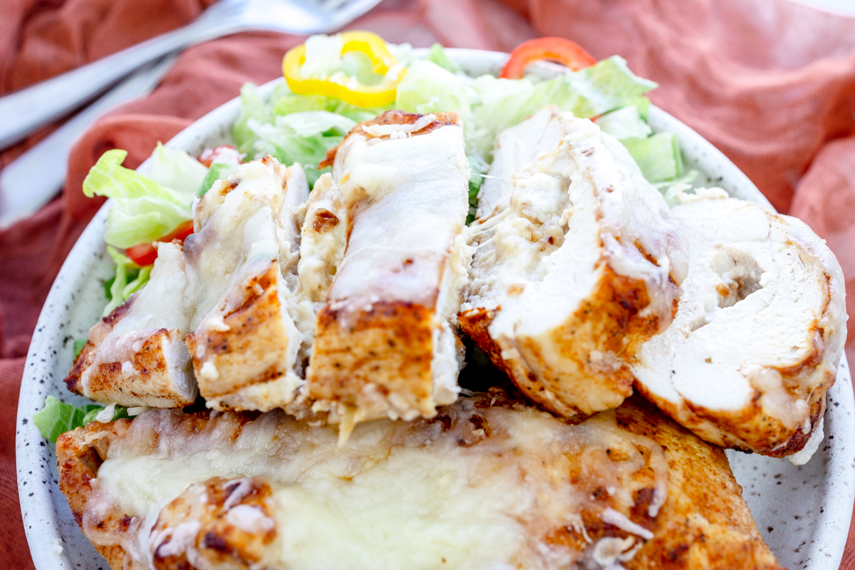 Close up overhead view of Air Fryer Stuffed Chicken on a plate with salad.