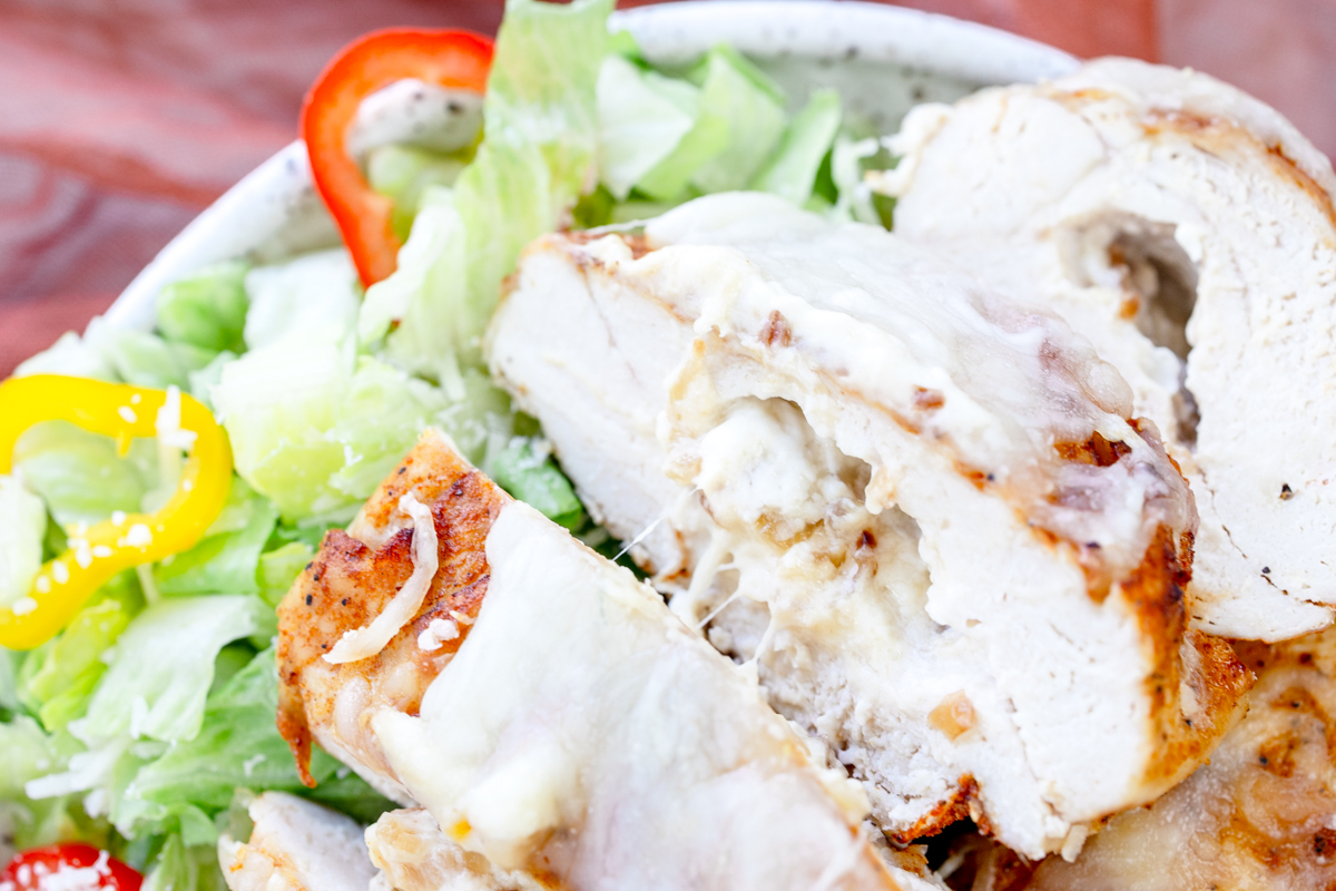 Close up overhead view of Air Fryer Stuffed Chicken on a plate with salad.