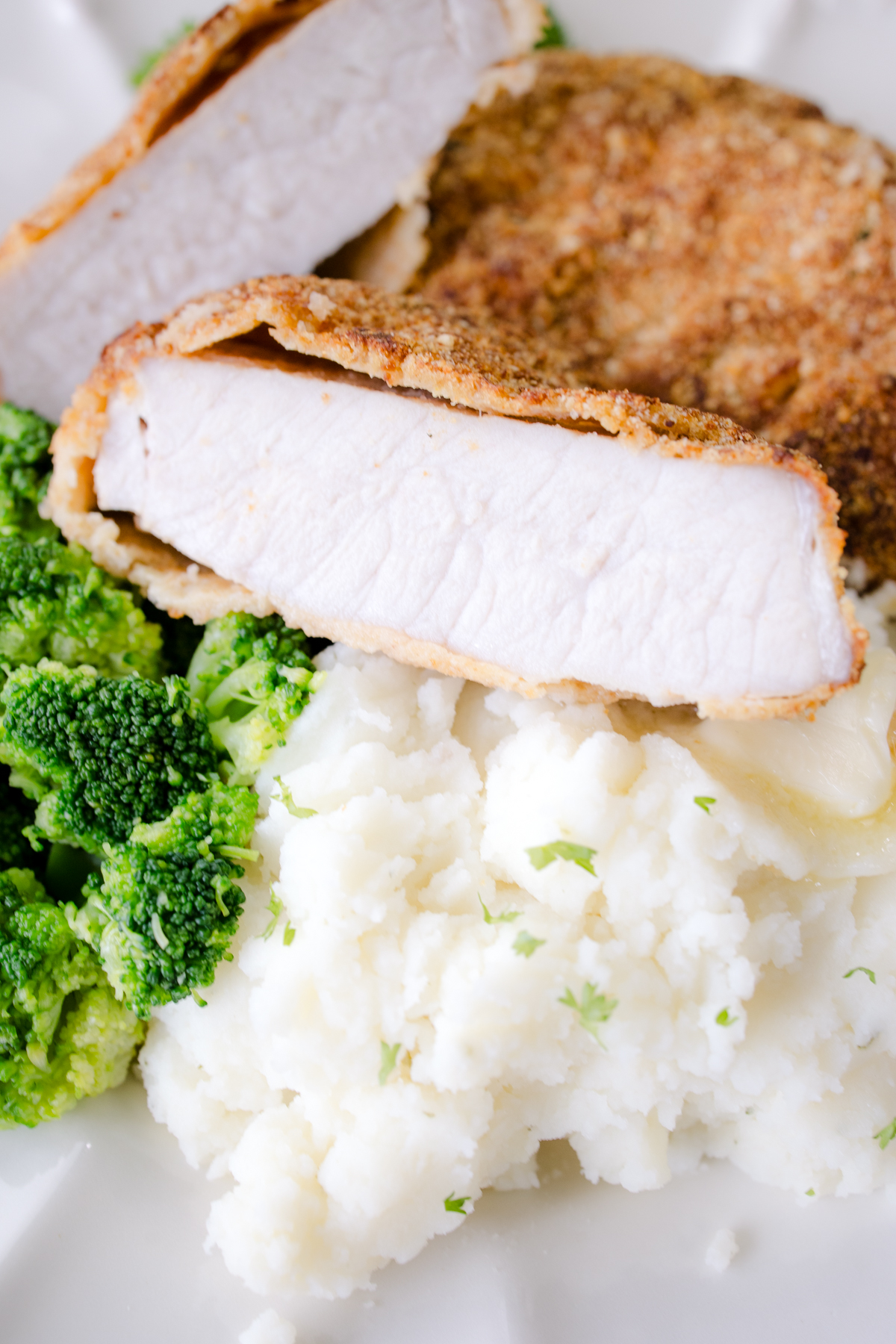 Crispy air fryer pork chops sliced and served with mashed potatoes and green beans.