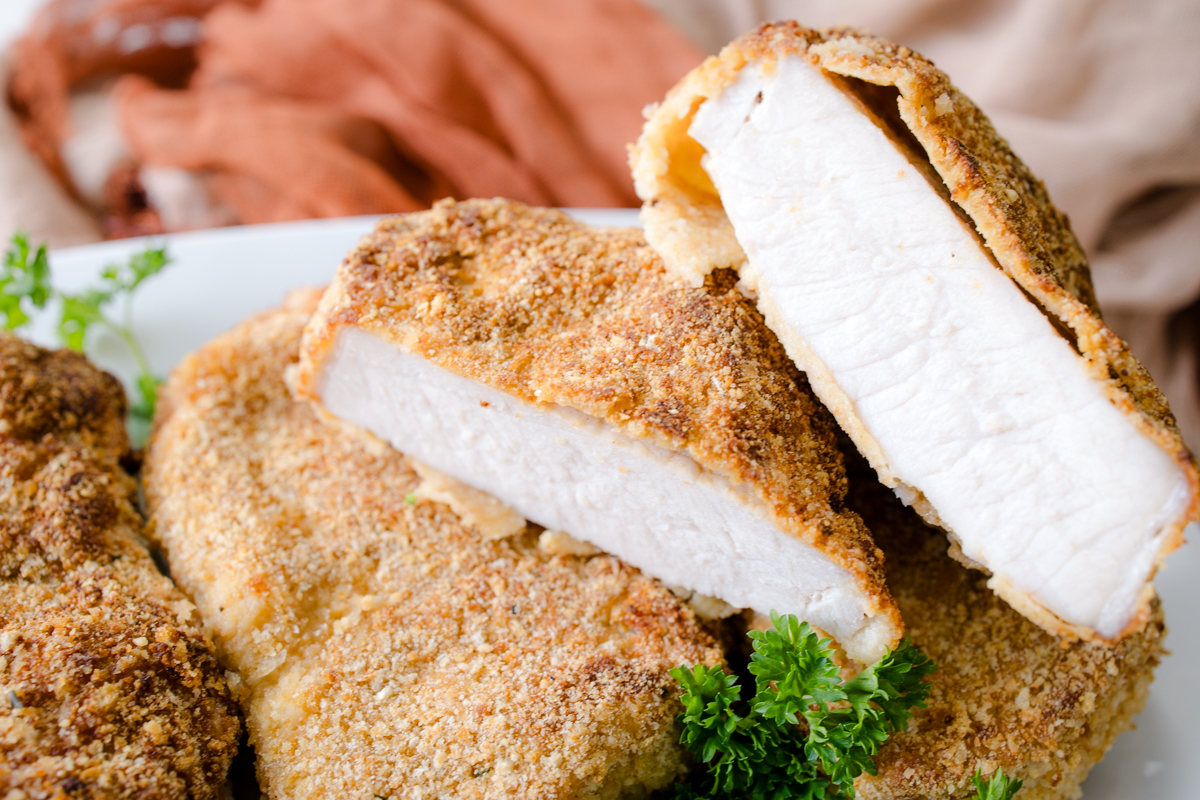 Sliced breaded pork chop showing juicy interior and crispy crust.