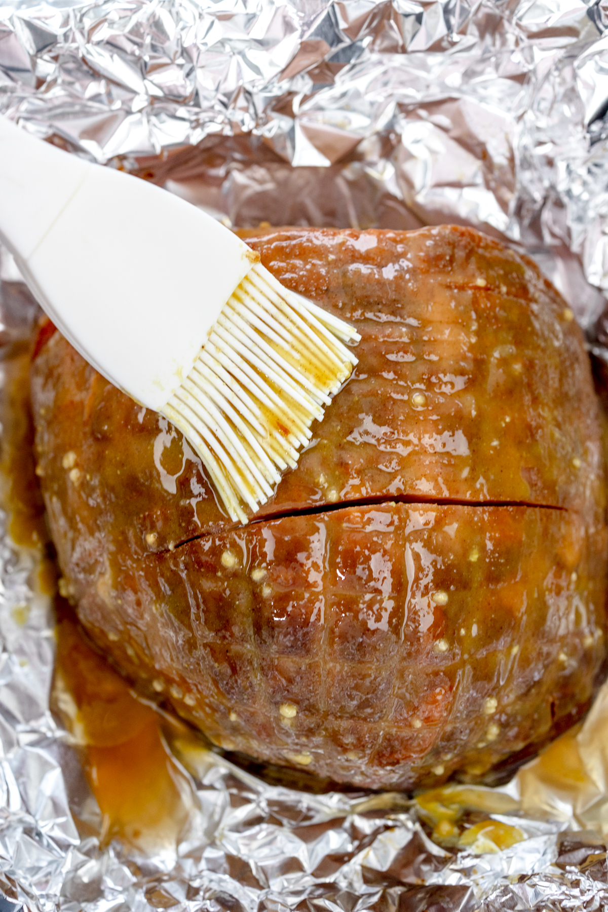 Overhead close up view of Air Fryer Ham being basted inside tinfoil.